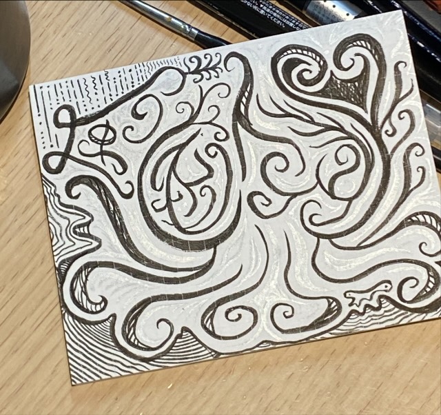 A small square of dense curvilinear pen pattern with lettering worked into the swirls